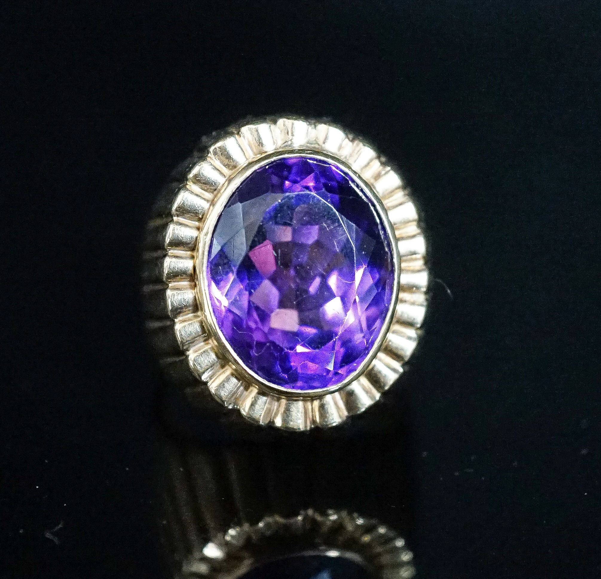 A yellow metal and oval cut amethyst set dress ring, with fluted setting, size Q/R, gross 17 grams.